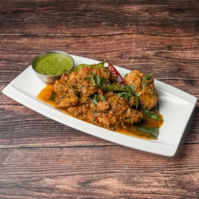 Mauli's Indian chicken curry with green herbs and red chilies, served with a side of green chutney.